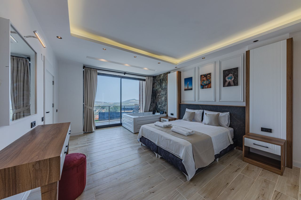 stats-img Modern hotel room with a large bed, hot tub, and scenic balcony view.