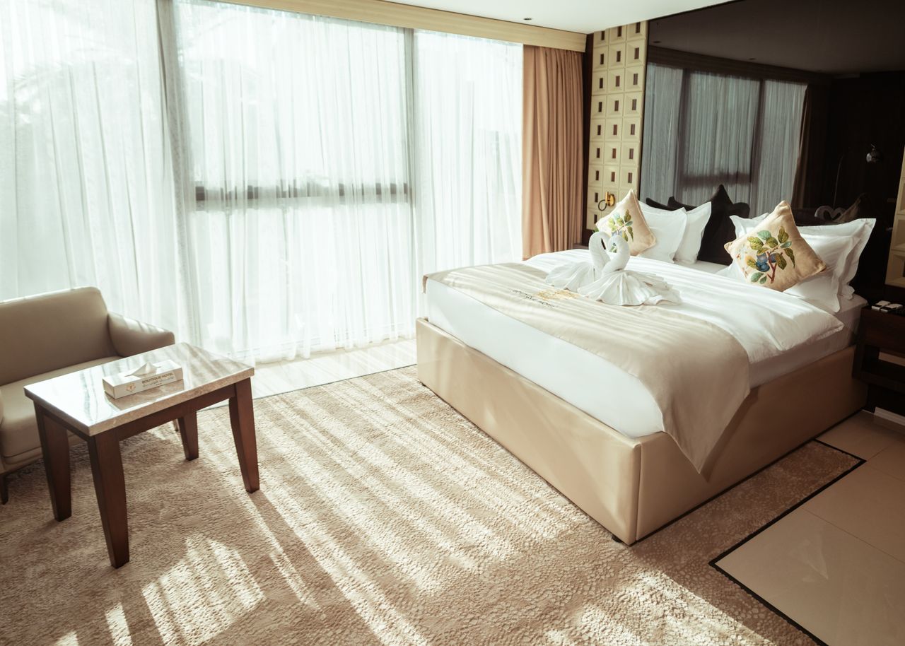 portfolio-03 Spacious hotel room with large bed, elegant decor, and natural light in Baghdad, Iraq.